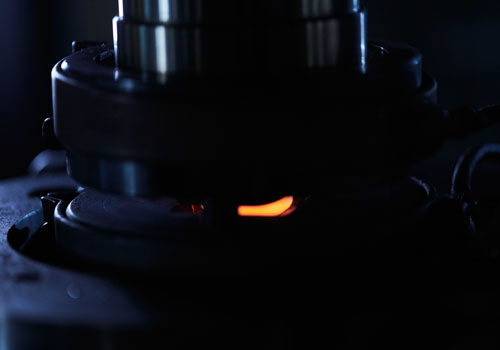 Lähikuva hehkuvasta metalliesineestä pimeässä ympäristössä.