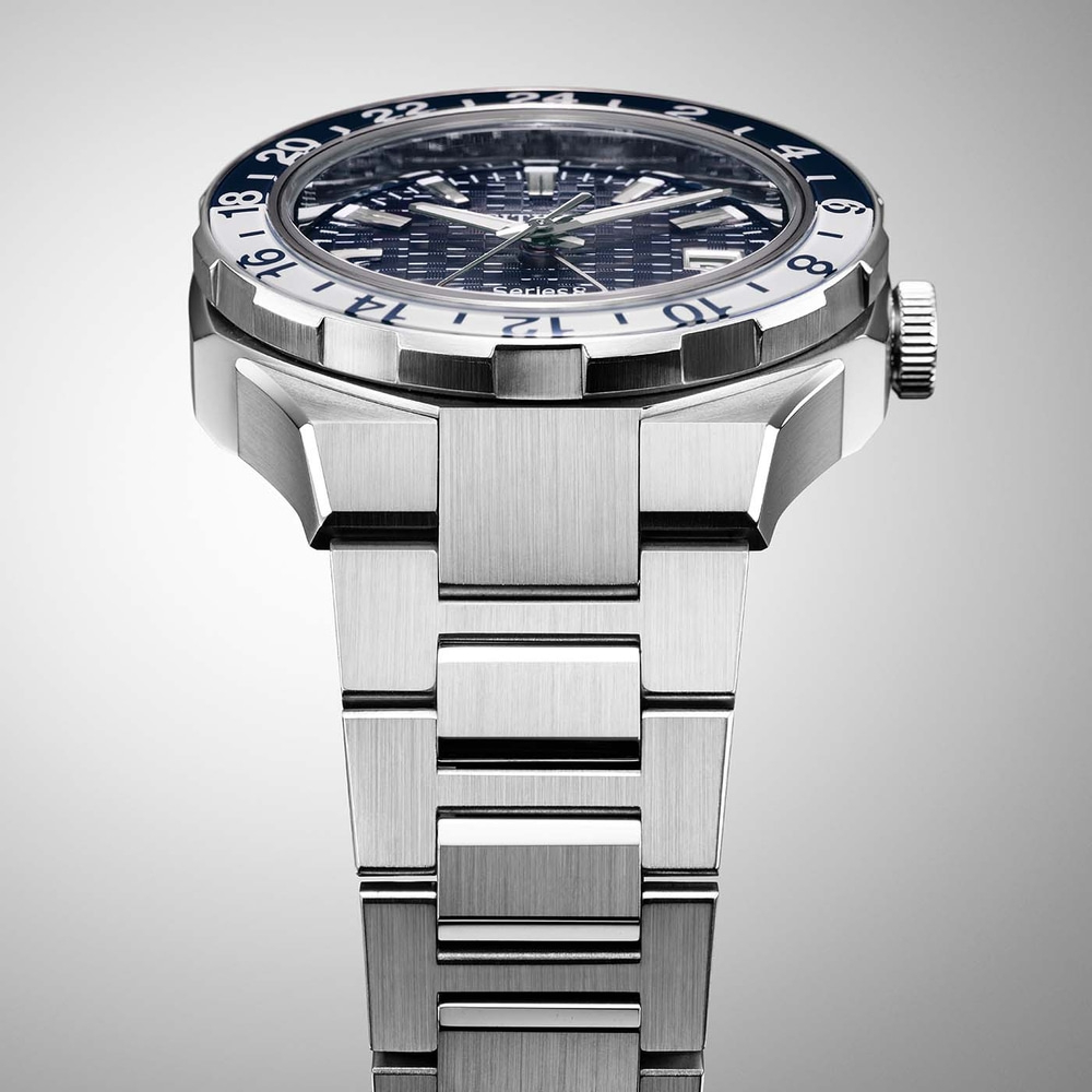 Lähikuva hopeisesta kellosta, jossa on sininen ja valkoinen kehys ja metallinen ranneke.