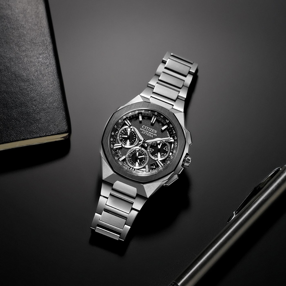 Citizen-kello mustalla pinnalla kynän ja muistikirjan kanssa.