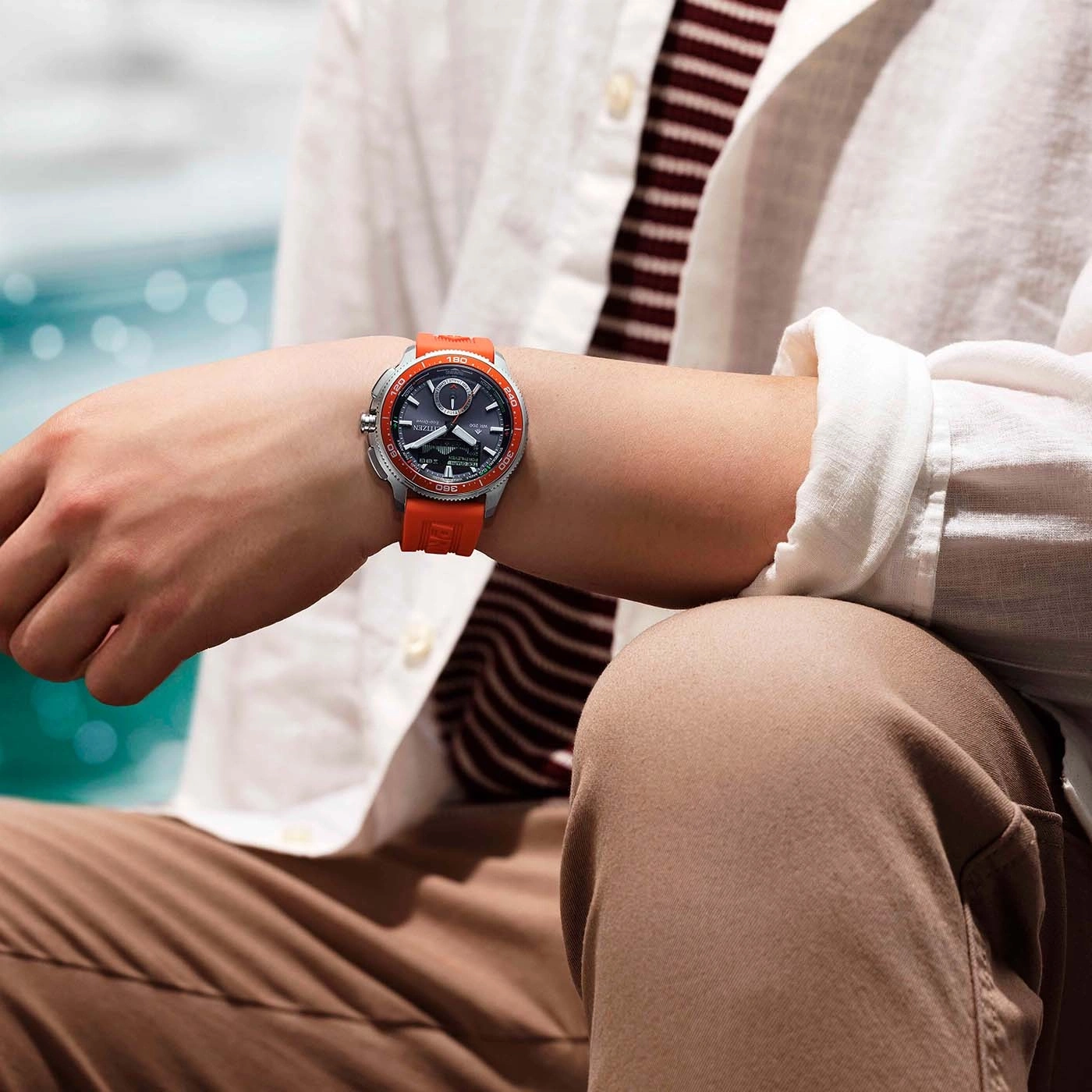 Mies käyttää Citizen Eco-Drive -kelloa oranssilla rannekkeella.
