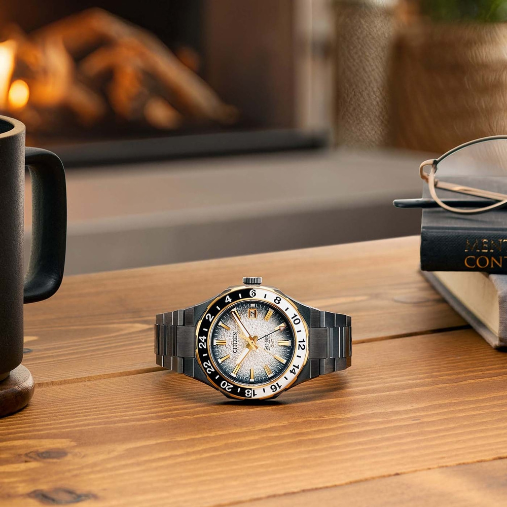 Kello puupöydällä mukin, lasien ja kirjan kanssa.