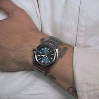 Miehen ranne Citizen Eco-Drive -kellolla ja tatuoinneilla.