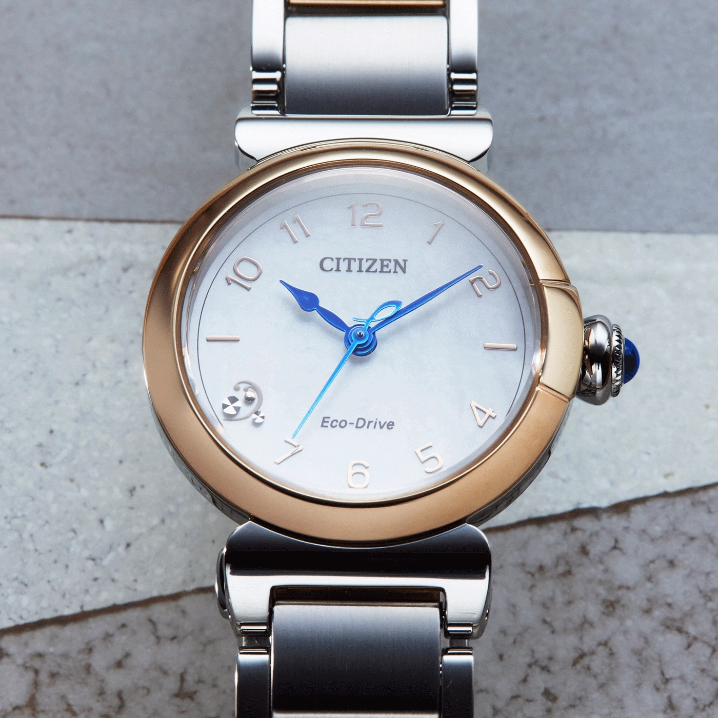 Citizen Eco-Drive -kello, jossa on kulta- ja hopearanneke ja siniset osoittimet.