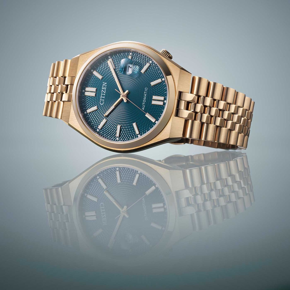 Kultainen Citizen-kello sinisellä kellotaululla ja heijastus pinnalla.