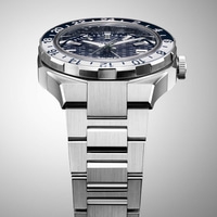 Lähikuva hopeisesta kellosta, jossa on sininen ja valkoinen kehys ja metallinen ranneke.