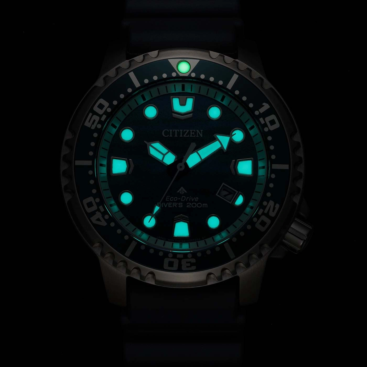 Kirkas vihreä Citizen Eco-Drive sukeltajankello hohtaa pimeässä.